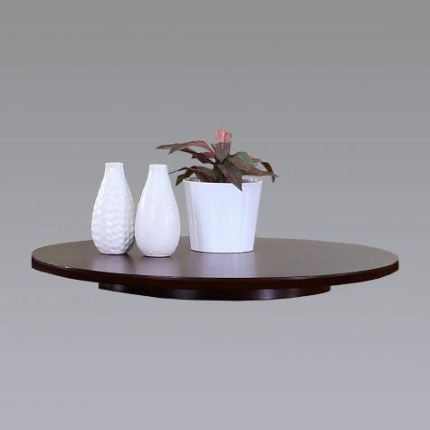 A dark walnut finish lazy susan shelf with a plant and two vases on top.