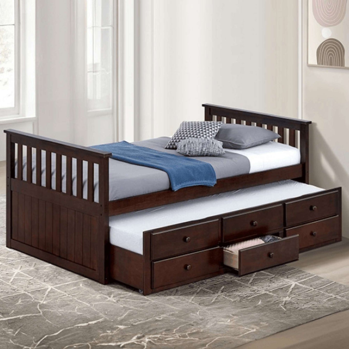 A dark walnut twin daybed with a trundle and three bottom drawers, displayed in a room setting with bedding and pillows.