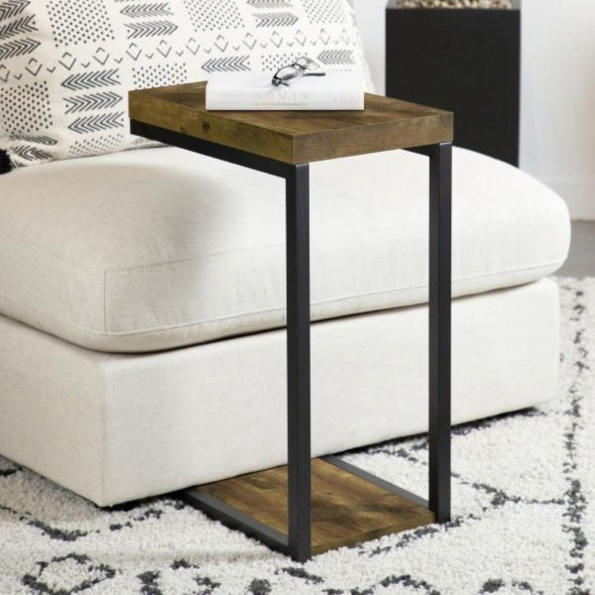 Edrice rustic nutmeg wooden end table with black metal legs and a lower shelf, styled next to a white sectional sofa on a patterned rug.