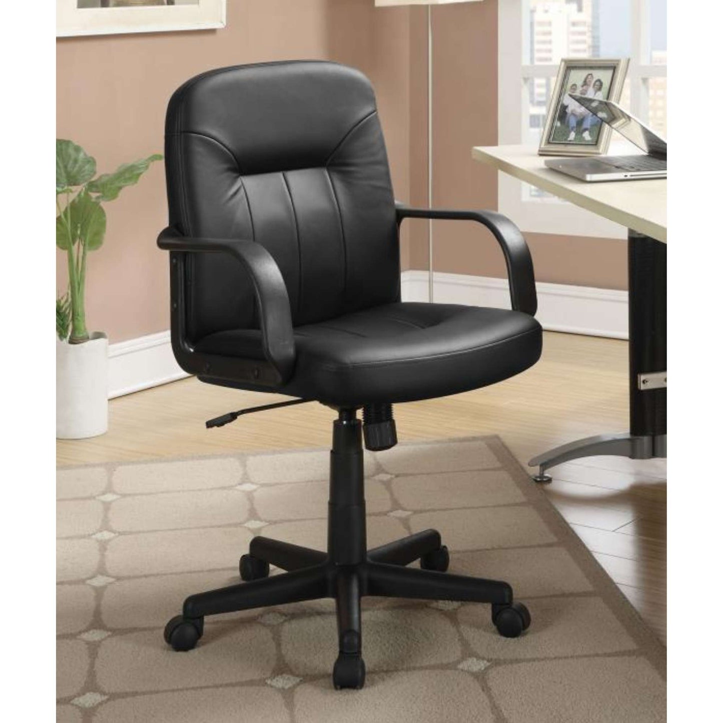 A black upholstered office chair with adjustable height settings and low profile arms, positioned in a home office setting.