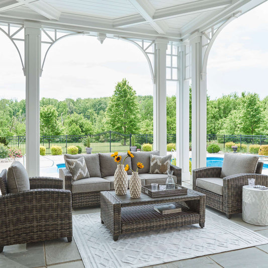 Gray Abinger 4 PC outdoor living set with the outdoor sofa, two outdoor arm chairs, and outdoor coffee table in an outdoor setting