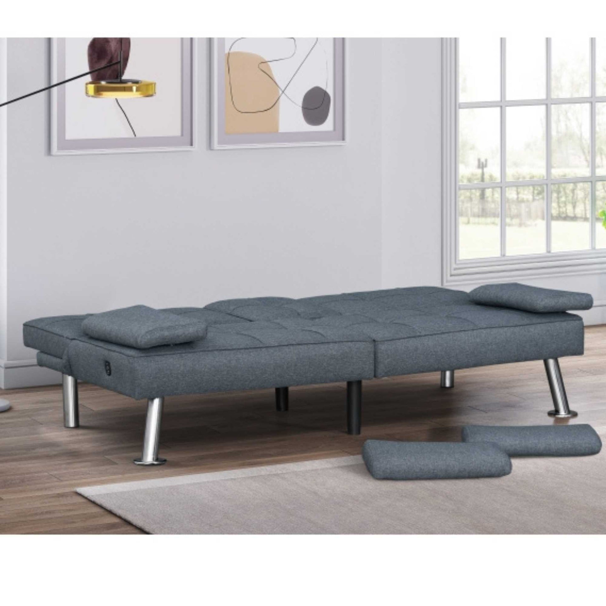 Gray sofa bed in a room with a window and wall art.