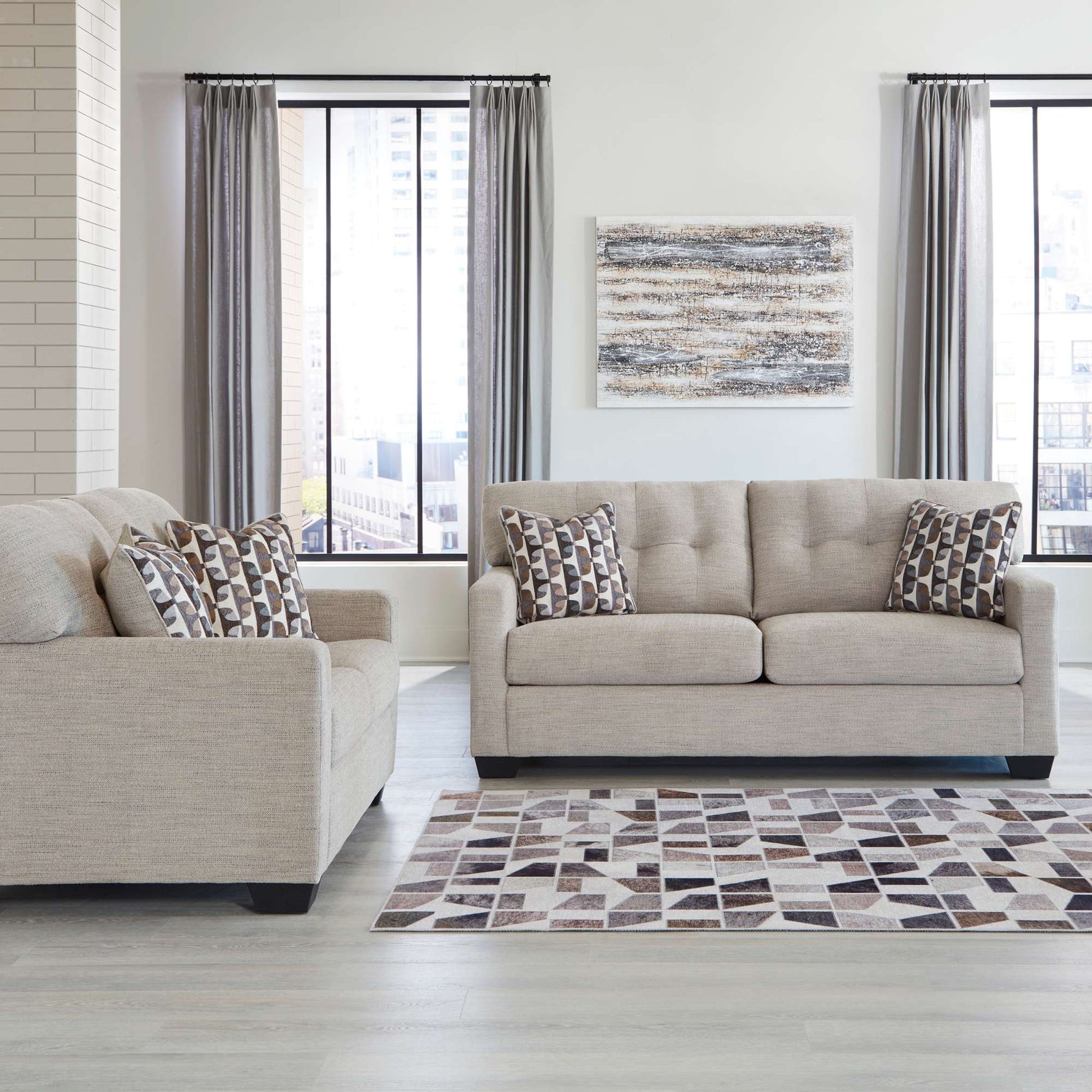 Calbex sofa and loveseat in pebble upholstery with patterned accent pillow in living room setting