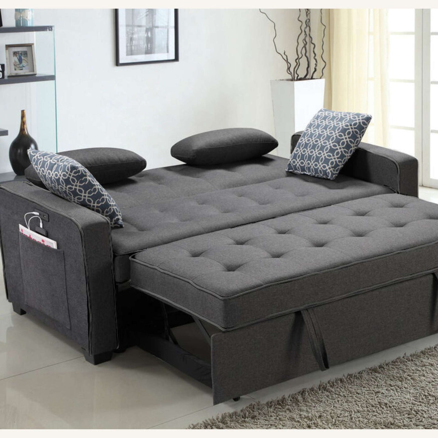 Gray sofa bed in a living room setting with pillows and a small table.