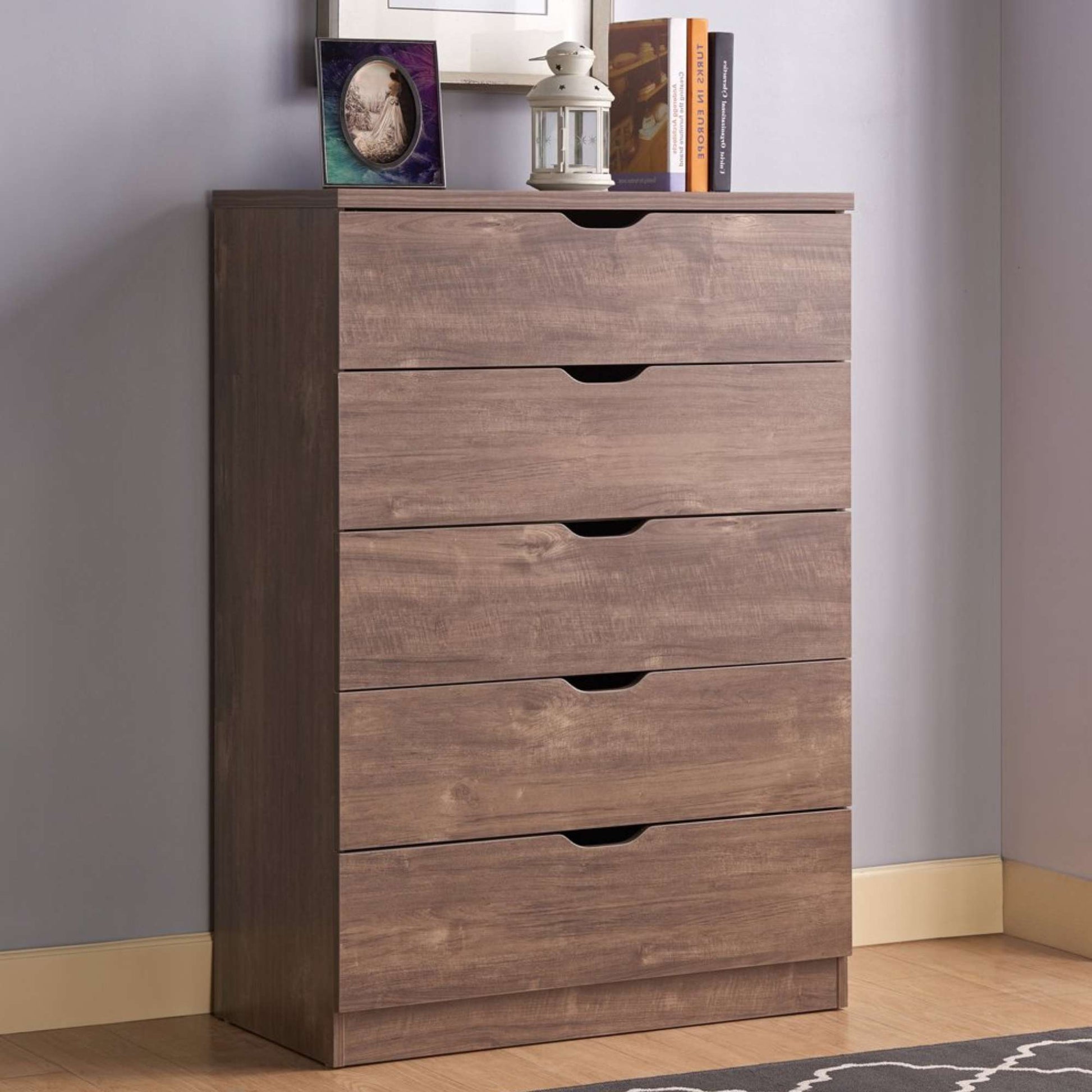 Wooden dresser with four drawers against a gray wall.