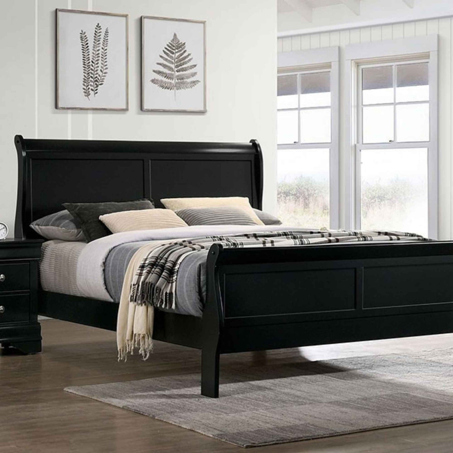 Black sleigh bed with bedding in a bedroom setting