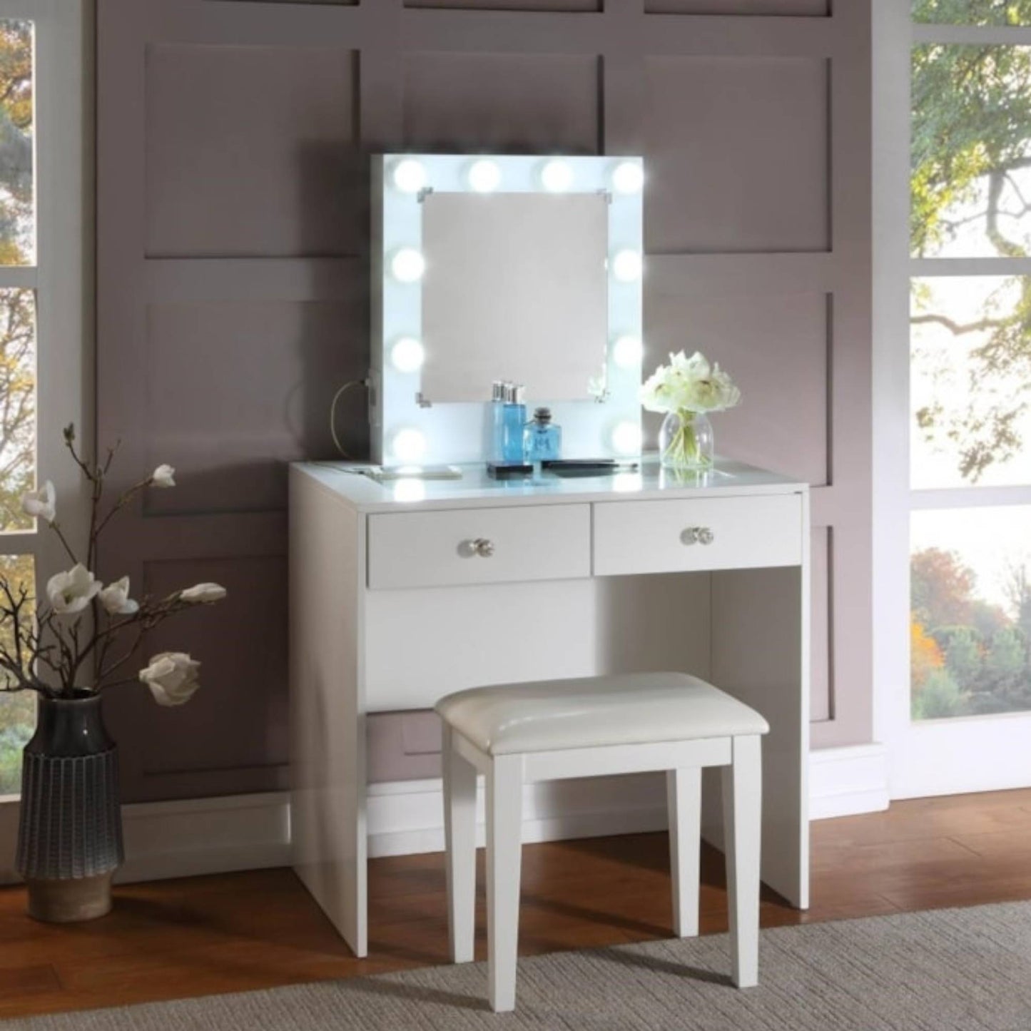 White Heartley vanity table with mirror and stool in a room with large windows.