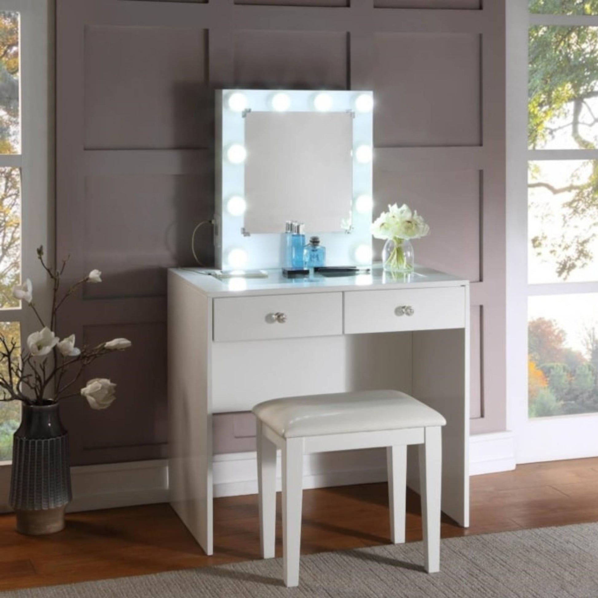 White Heartley vanity table with mirror and stool in a room with large windows.