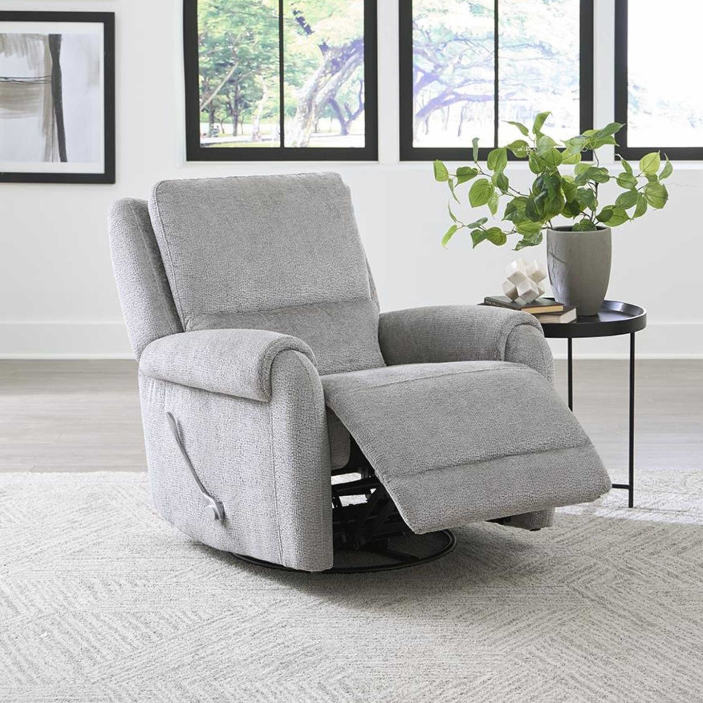 A gray Hinwitz glider swivel recliner chair positioned in a living room setting with a plant on the side.