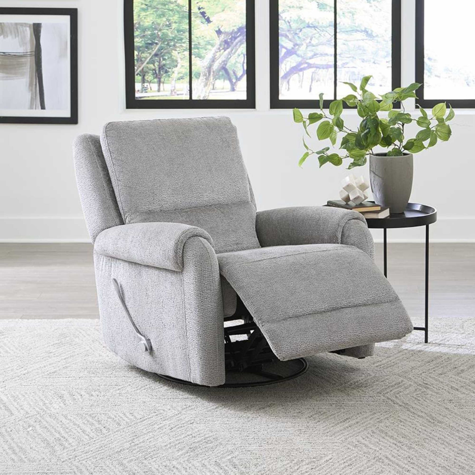 A gray Hinwitz glider swivel recliner chair positioned in a living room setting with a plant on the side.
