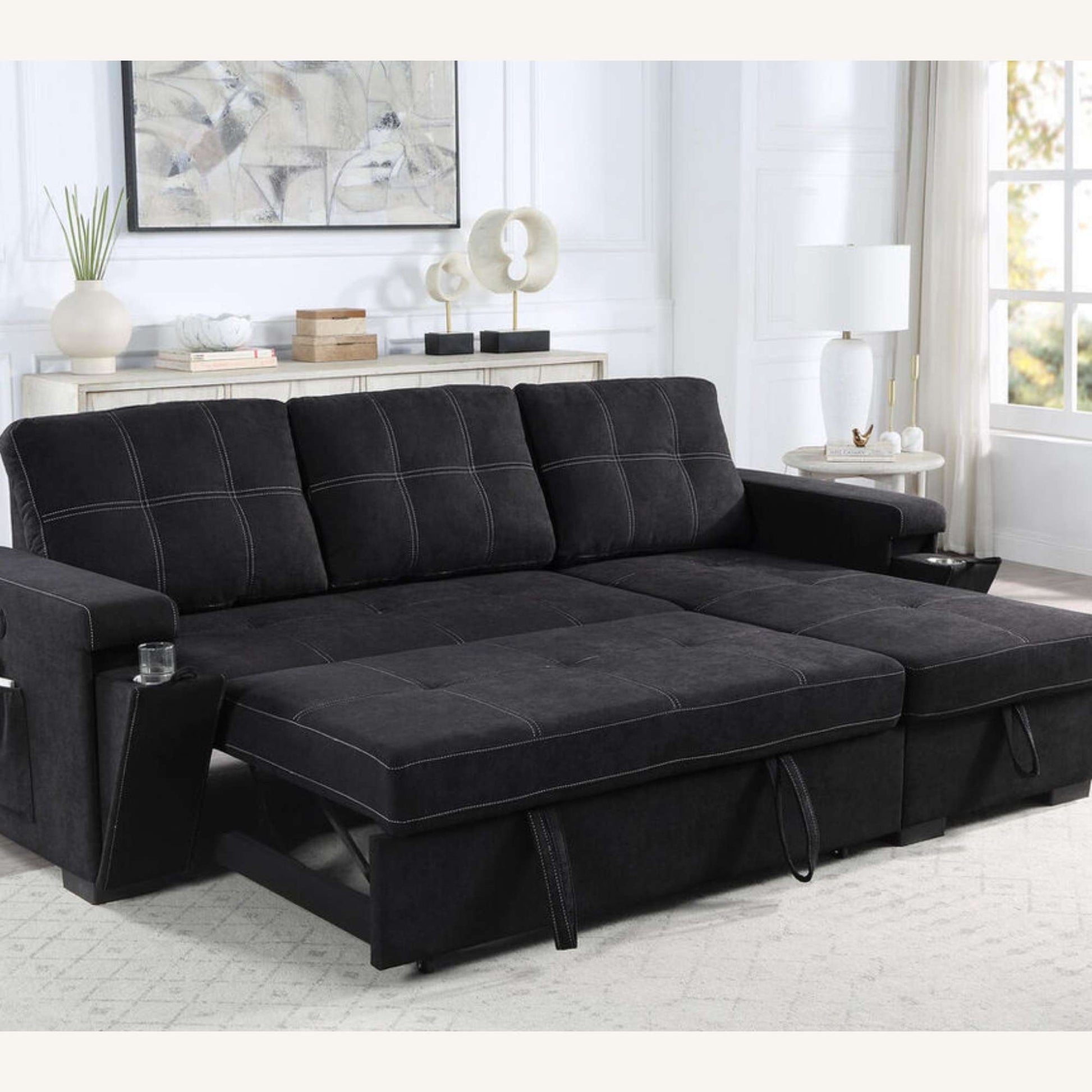 Black pullouts sleeper sectional sofa in a living room setting with decor elements.