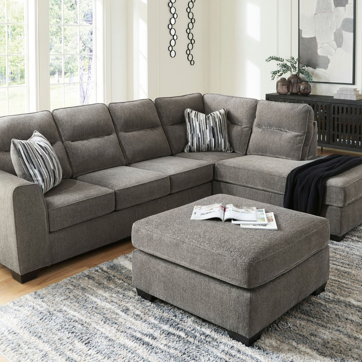 Graphite grey Loxley sectional with right-facing chaise with geometric accent pillows in living room setting with blanket accent
