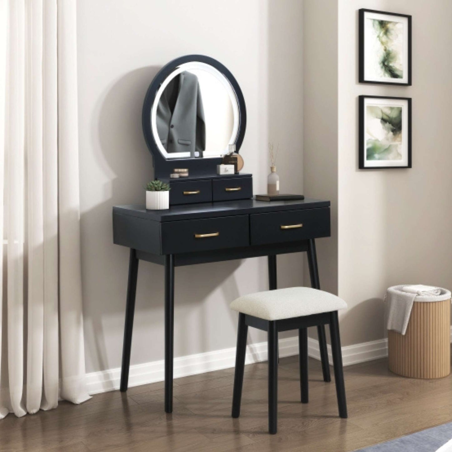 Black vanity table with round mirror and stool in a room setting