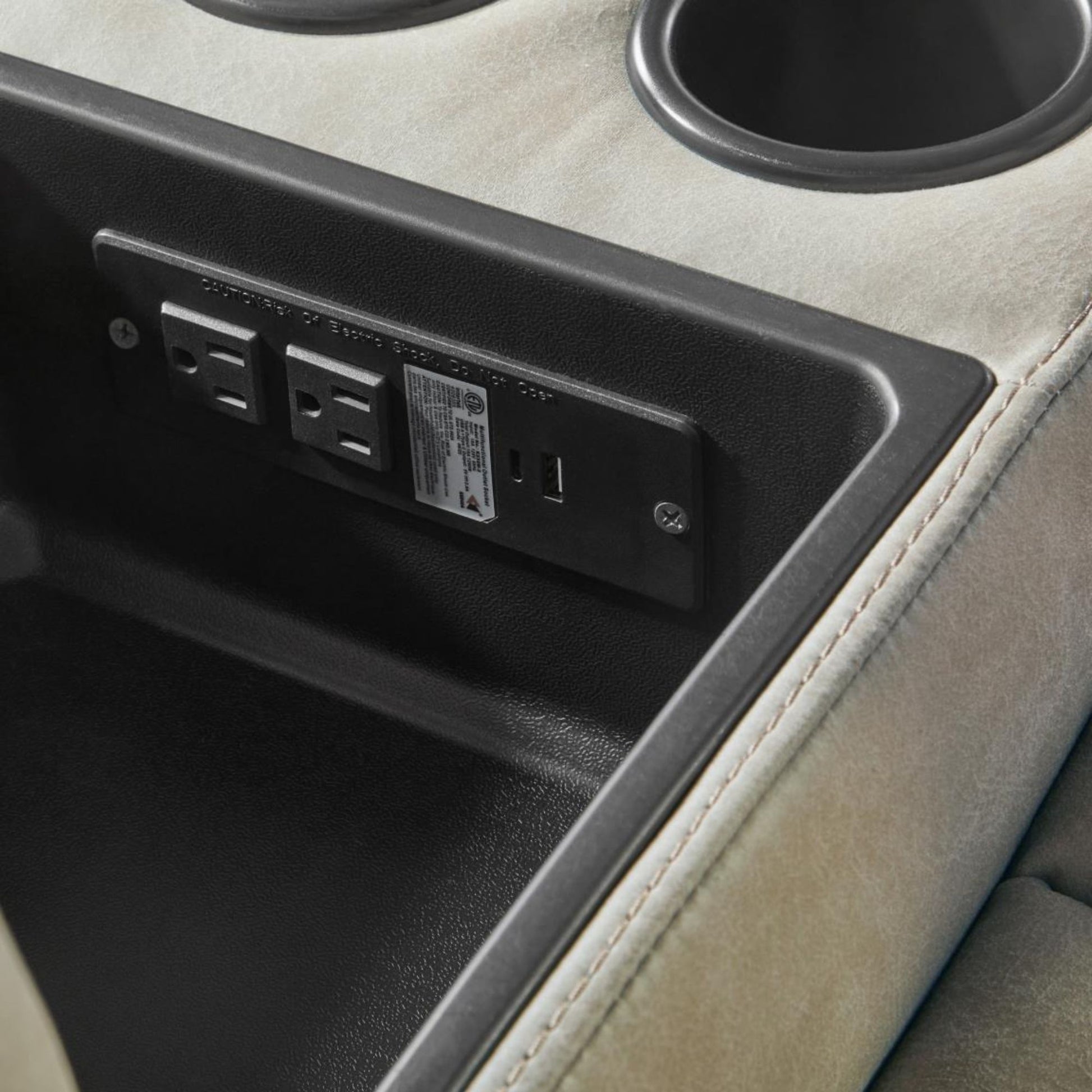 Close-up of a Potrero storage console storage compartment showing a black power outlet panel with two electrical outlets and a USB port