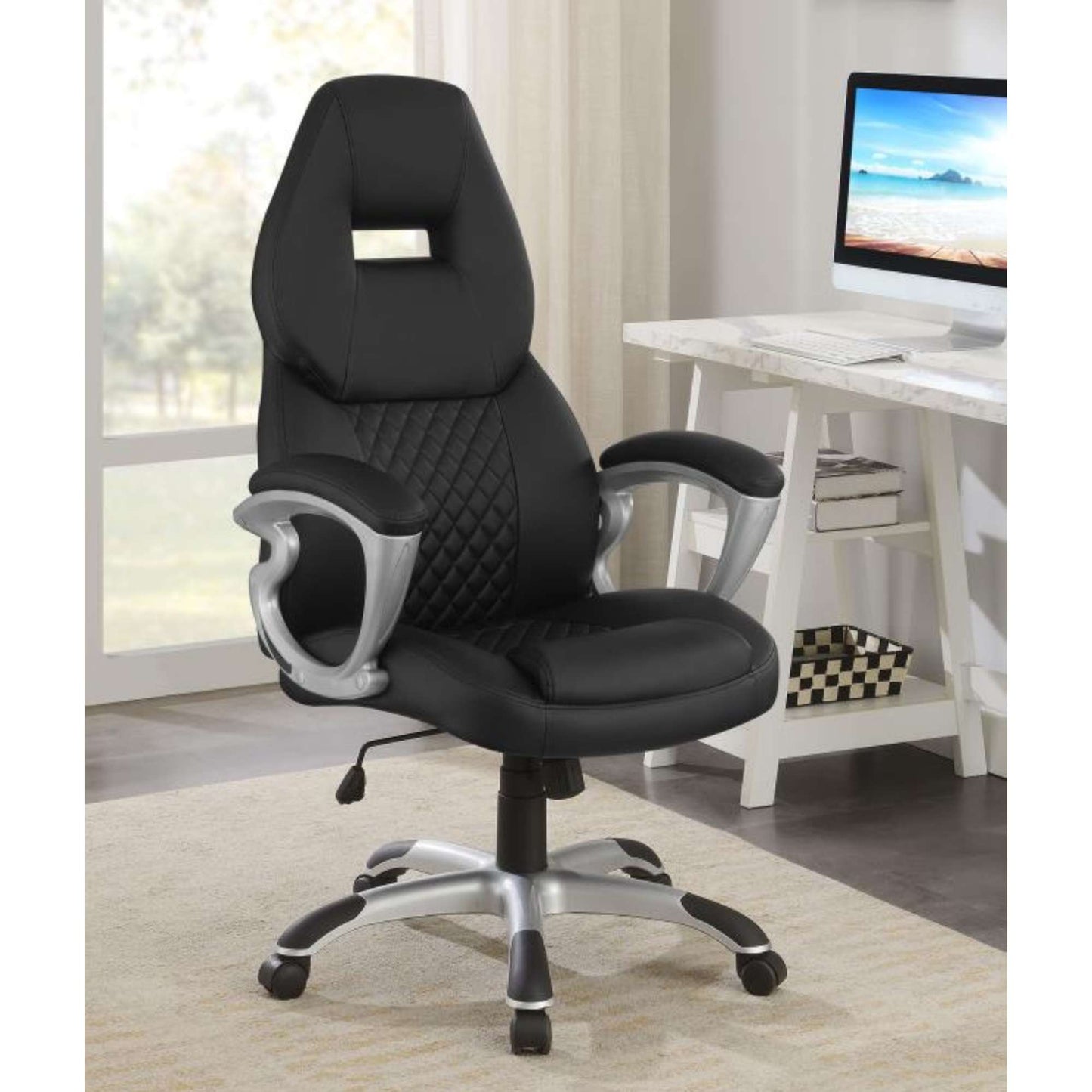 A black adjustable height office chair with padded armrests and a high headrest, placed in a home office setting.
