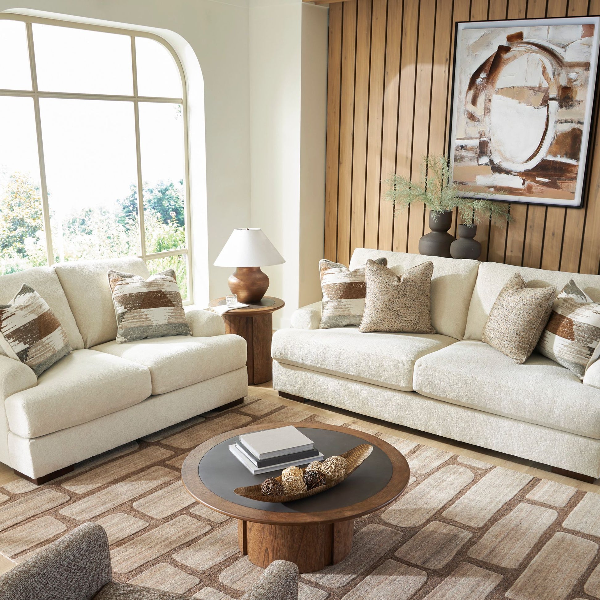 Sarabi sofa and loveseat set in sand upholstery with neutral multi-colored accent pillows in living room setting