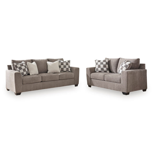 A Teelgan two-piece living room furniture set consisting of a three-seat sofa and a two-seat loveseat in a textured taupe fabric, styled with gray and white patterned throw pillows, on a solid white background.