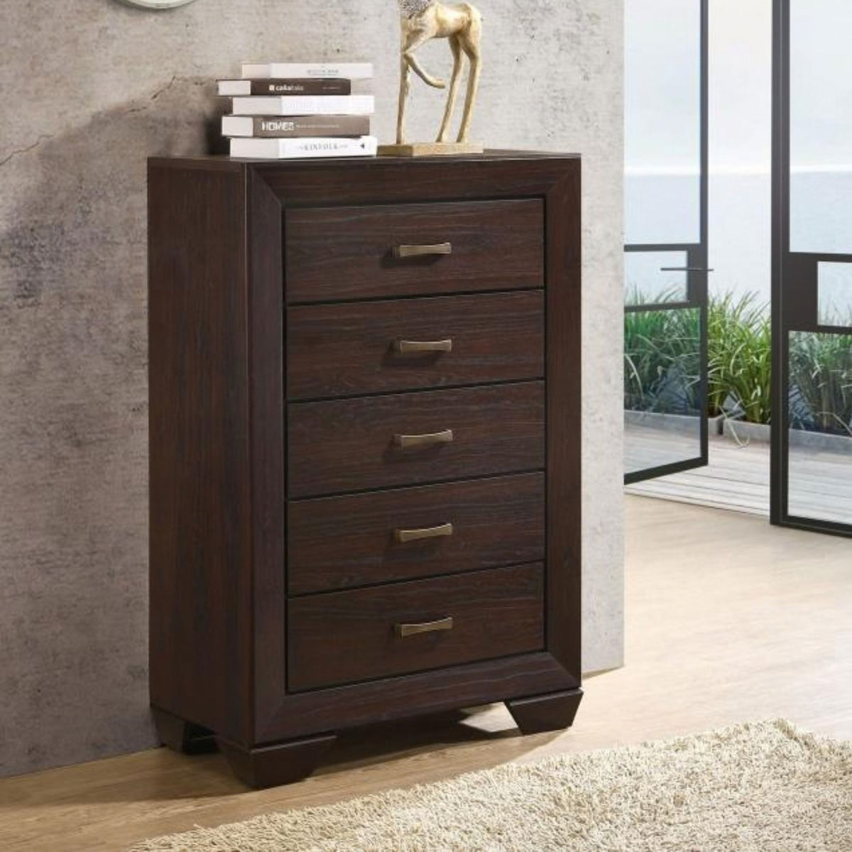 Tennos dark cocoa brown chest with five drawers in bedroom setting with books and a figure on top. 